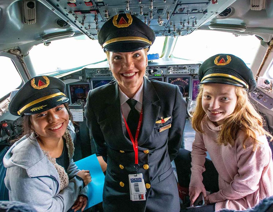 Pilota donna in cabina di pilotaggio con due partecipanti al programma